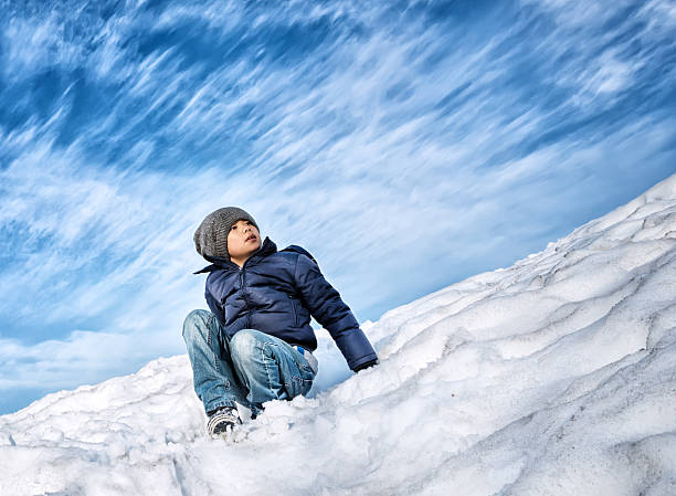 Young Asian boy wearing down jacket and winter hat in cold winter environment.