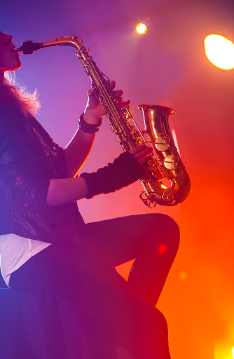 Young woman playing saxophone at the nightclub