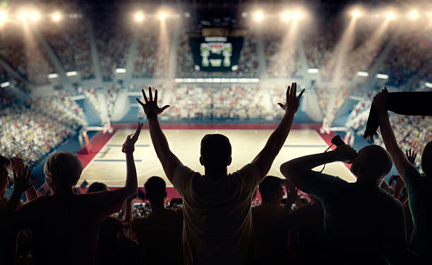 Basketball fans at basketball arena Basketball fans celebrating at a basketball game. We see their silhouettes and fans attributes basketball sport stock pictures, royalty-free photos & images