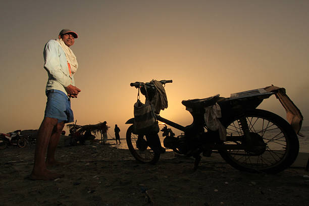 Working man waits near his motorcycle at Derrumbao Beach stock photo