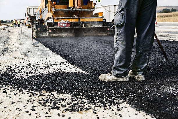 Man's legs on newly laid asphalt during road construction Worker operating asphalt paver machine during road construction and repairing works black tar stock pictures, royalty-free photos & images