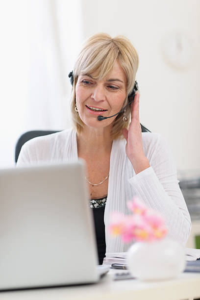 istock middle age business woman with headset working on laptop 469587938