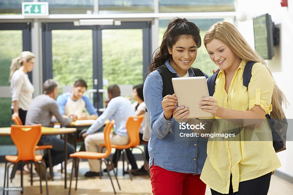 Two Female Teenage Students In Classroom With Digital Tablet Two Female Teenage Students In Classroom With Digital Tablet During Lesson Classroom Stock Photo