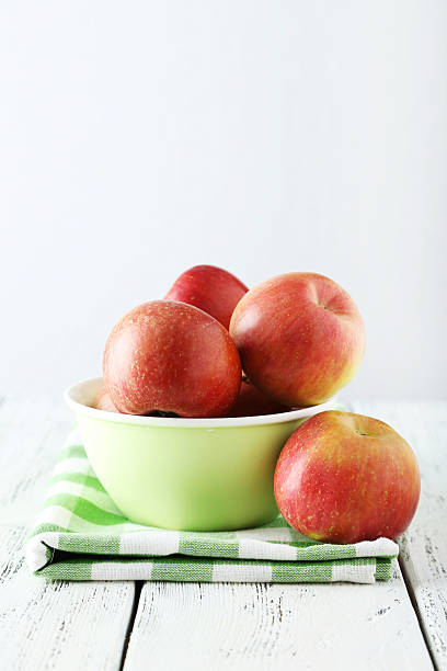 istock Apples in bowl on white wooden background 469591096