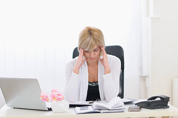 istock stressed middle age business woman sitting at office table 469591546