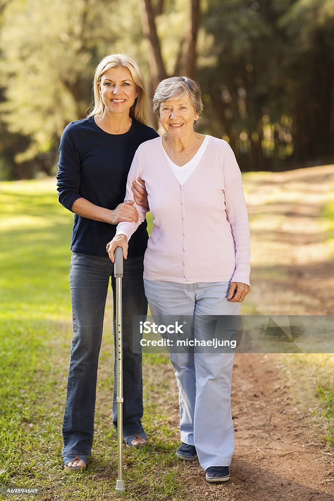 senior woman and caring daughter walking in forest smiling senior woman and caring daughter walking in forest Daughter Stock Photo