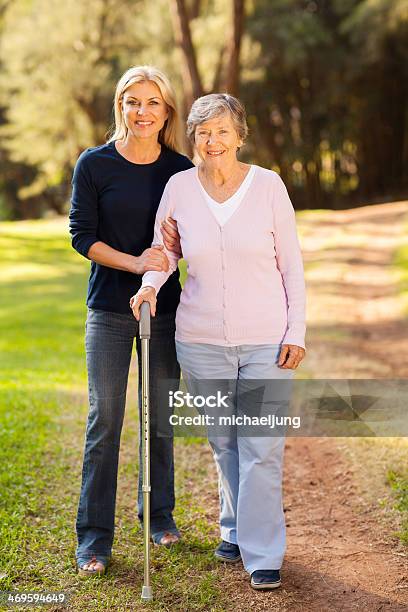 Senior Woman And Caring Daughter Walking In Forest Stock Photo - Download Image Now - Daughter, Mother, Walking