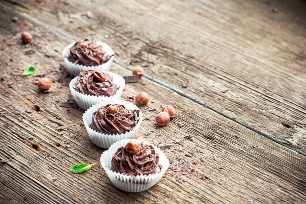 istock Row of chocolate cupcakes with hazelnuts on top. Wooden background. 469598044
