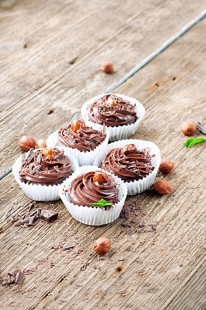 istock Five chocolate cupcakes with hazelnuts on top. Wooden background. 469598058