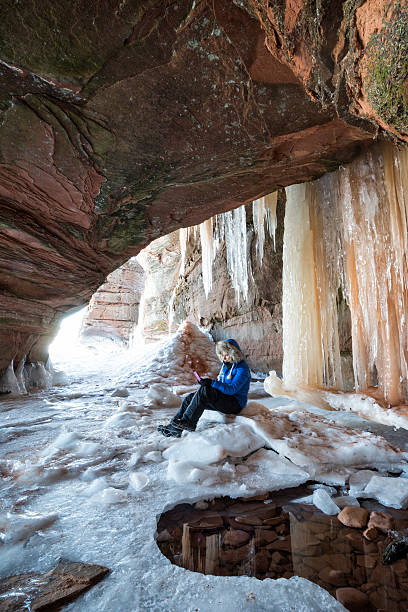 Woman texting from inside an ice cave at Apostle Island National Lakeshore, Cornucopia, Bayfield County, Wisconsin, USA