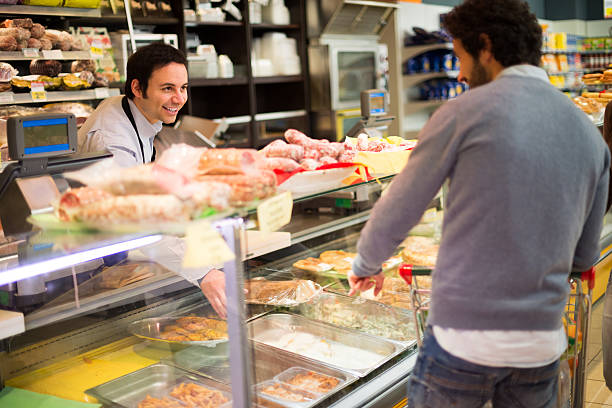 shopkeeper mit einem kunden - feinkostgeschäft stock-fotos und bilder