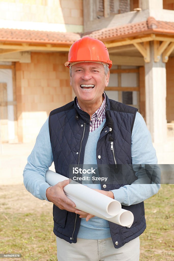 Portrait of senior engineer Senior architect standing in front of built structure and holding blue print. Small business. 2015 Stock Photo