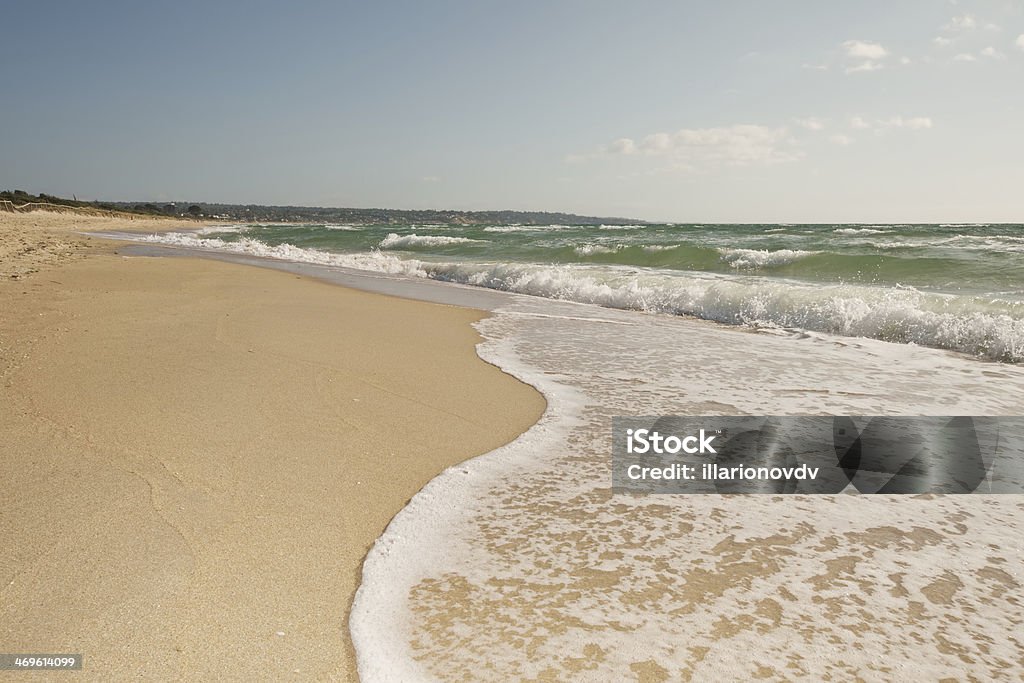 Breaking wave curve Breaking wave curve on sandy beach in motion with bubbles, splashes, coastline and light clouds over blue sky Australia Stock Photo