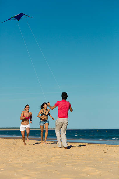 istock Man and women running on beach with kite 469621191