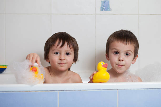 deux garçons jouant dans la baignoire avec canards en caoutchouc - male animal duck water cleaning photos et images de collection