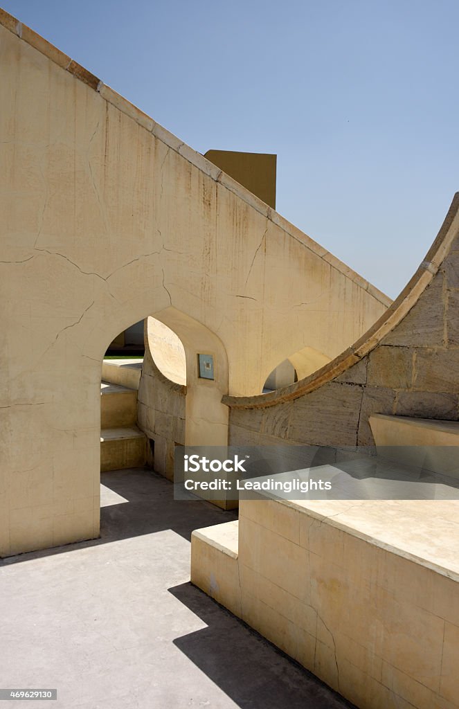 Sundial at Jantar Mantar in Jaipur A sundial at the Jantar Mantar at Jaipur, Rajasthan, India. This particular instrument is aligned to the constellation Aries as shown by the ram symbol beneath the arch. The Jantar Mantar is a collection of architectural astronomical instruments, one of several collections built in India in the early eigtheenth century, many of which are of monumentsl size. The name is derived from jantar ("instrument"), and mantar ("formula" or "calculation"). The observatory consists of up to twenty major geometric devices for measuring time, predicting eclipses, tracking star locations as the earth orbits around the sun, ascertaining the declinations of planets, and determining the celestial altitudes and related ephemerides. Each is a fixed and 'focused' tool. They are also used to this day to calculate auspicious dates for life events such as weddings and births. 18th Century Stock Photo