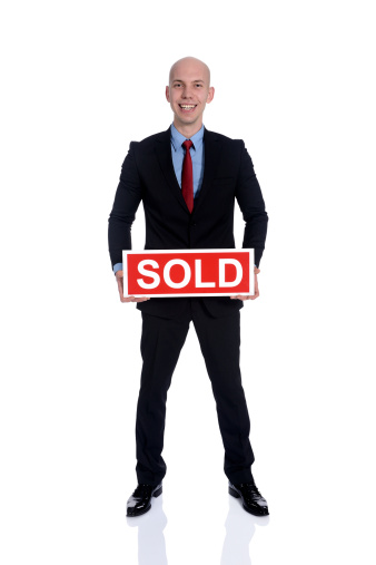 Smiling businessman holding a red sold card isolated on white.