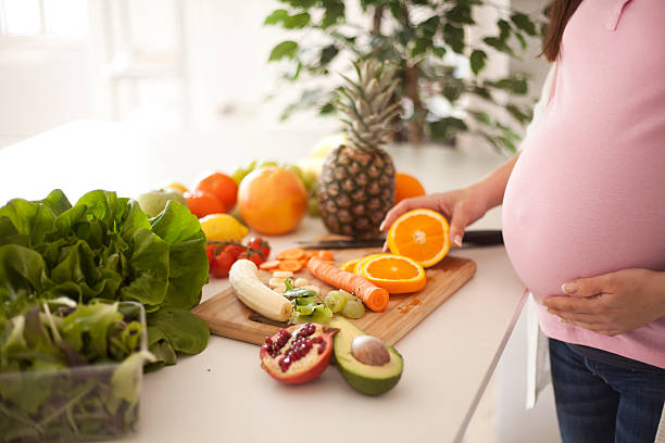 Pregnant woman preparing healthy fruits and vegetables stock photo