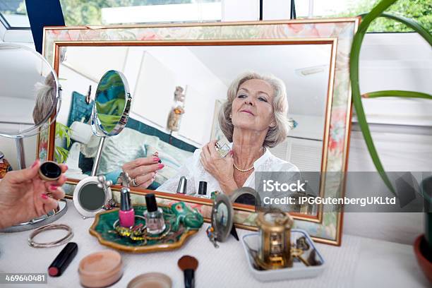 Mirror Reflection Of Senior Woman Spraying Perfume On Herself Stock Photo - Download Image Now