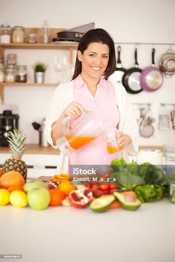 Pregnancy and nutrition Beautiful smiling pregnant woman making a healthy drink using fruits and vegetable. 2015 Stock Photo