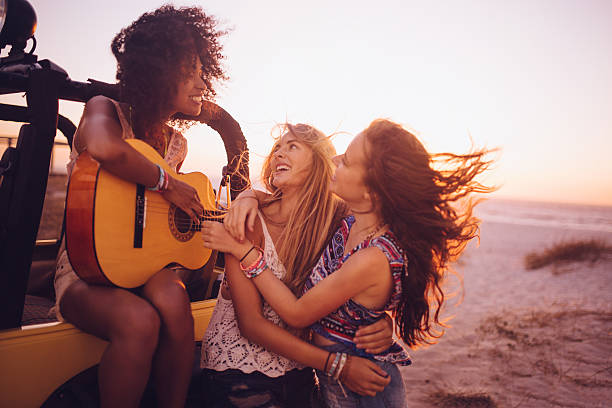 afro dziewczyna gra na gitarze dla jej przyjaciół o zachodzie słońca - travel adolescence road trip outdoors zdjęcia i obrazy z banku zdjęć