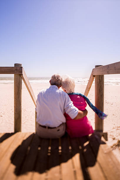 istock Elderly retired couple sitting together affectionately at the beach 469641066