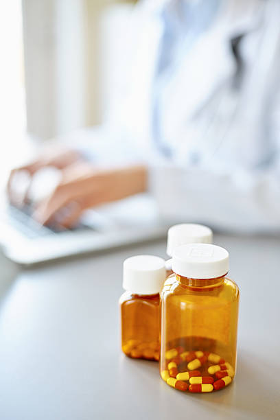 istock Perscription pill bottle on desk with doctor using laptop 469645402