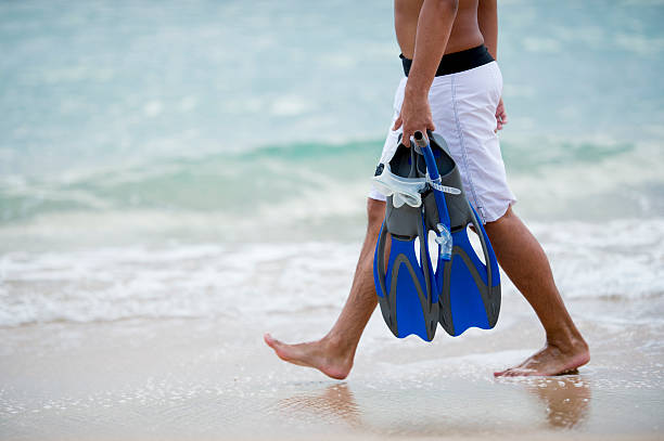 Man on vacation walking barefoot on a beach in Hawaii.