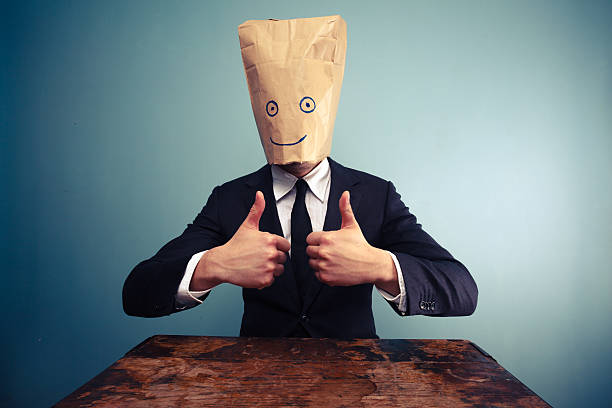 A businessman wearing a paper bag with a smile over his head Businessman with bag over head giving thumbs up signs and symbols stock pictures, royalty-free photos & images