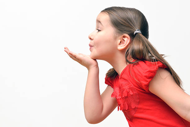 Little girl blowing kisses Sweet little girl blowing kisses, wearing a red t-shirt with hearts. blowing a kiss stock pictures, royalty-free photos & images