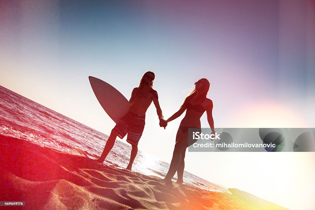 Couple on the beach Silhouette of couple in love walking on the beach carrying surfboard and holding hands. Lomo photo effect 2015 Stock Photo