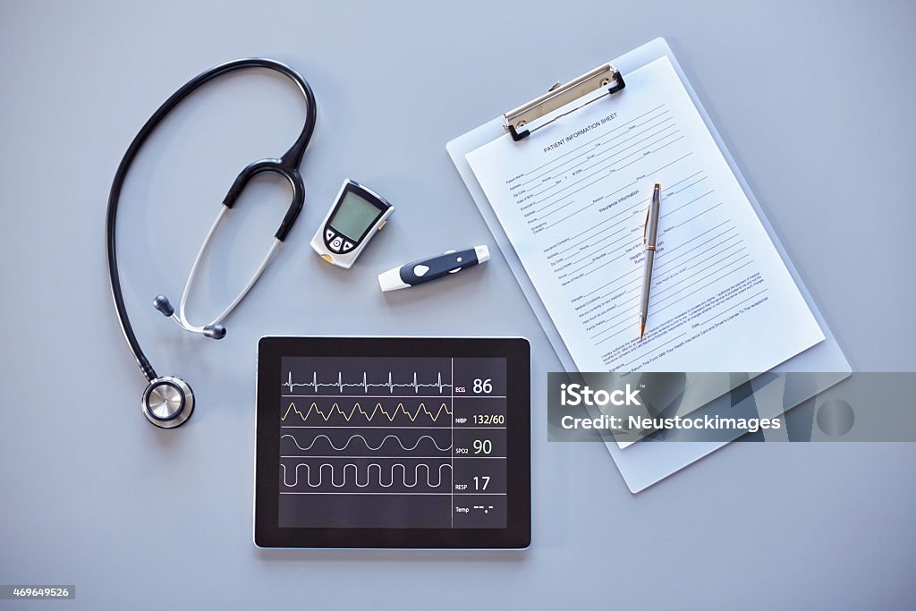 Clipboard, stethoscope, glucometer and digital tablet on desk High angle image of clipboard, stethoscope with glucometer and digital tablet on desk in clinic. Tablet PC is displaying heart monitor screen. Blood Sugar Test Stock Photo