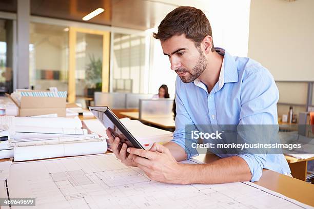 Male Architect With Digital Tablet Studying Plans In Office Stock Photo - Download Image Now