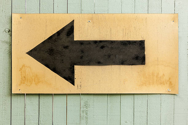 istock Sign with black arrow painted on obsolete card board. 469654660