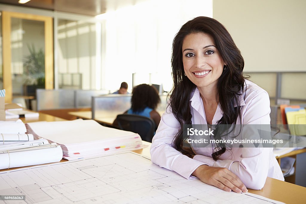 Female Architect Studying Plans In Office Female Architect Studying Plans In Office Smiling At Camera Latin American and Hispanic Ethnicity Stock Photo