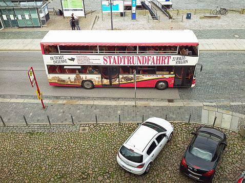 Dresden, Germany-September 30, 2014: Top view on city tour bus moving in city waterfront.  Trip offers route with 22 different stops in Dresden. This picture was taken from Bruhl Terasse.
