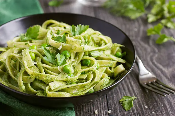 Tagliatelle pasta with spinach and green peas pesto, selective focus