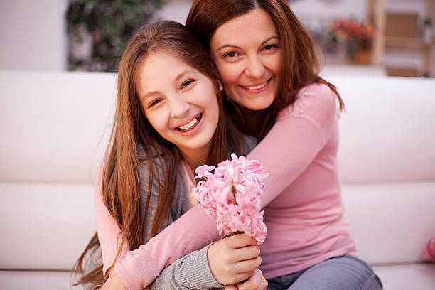 Mother and daughter gently hugged. They are very happy, laughing and daughter holding flowers hyacinth