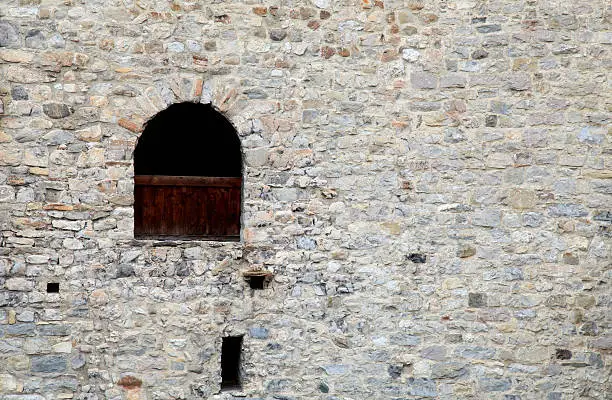 Photo of window in old stone  wall of medieval castle