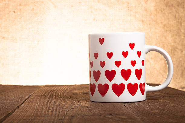 istock White mug with hearts on old wooden table against background 469676062