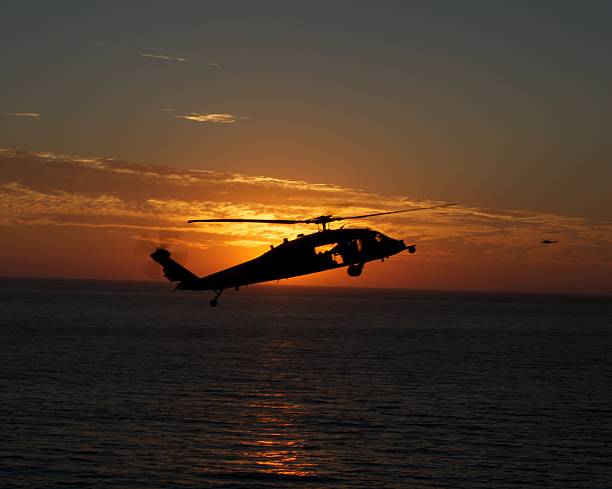 istock Sea Hawk helicopter flies past setting sun over ocean 469681253