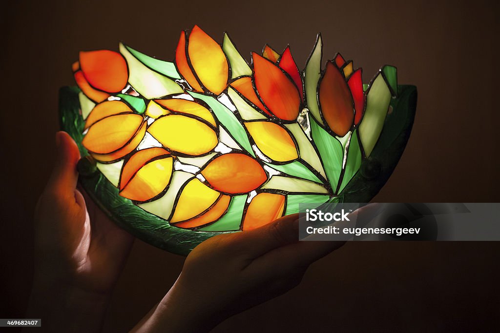 Handmade stained glass lamp with tulips flowers in woman's hands Electric Lamp Stock Photo