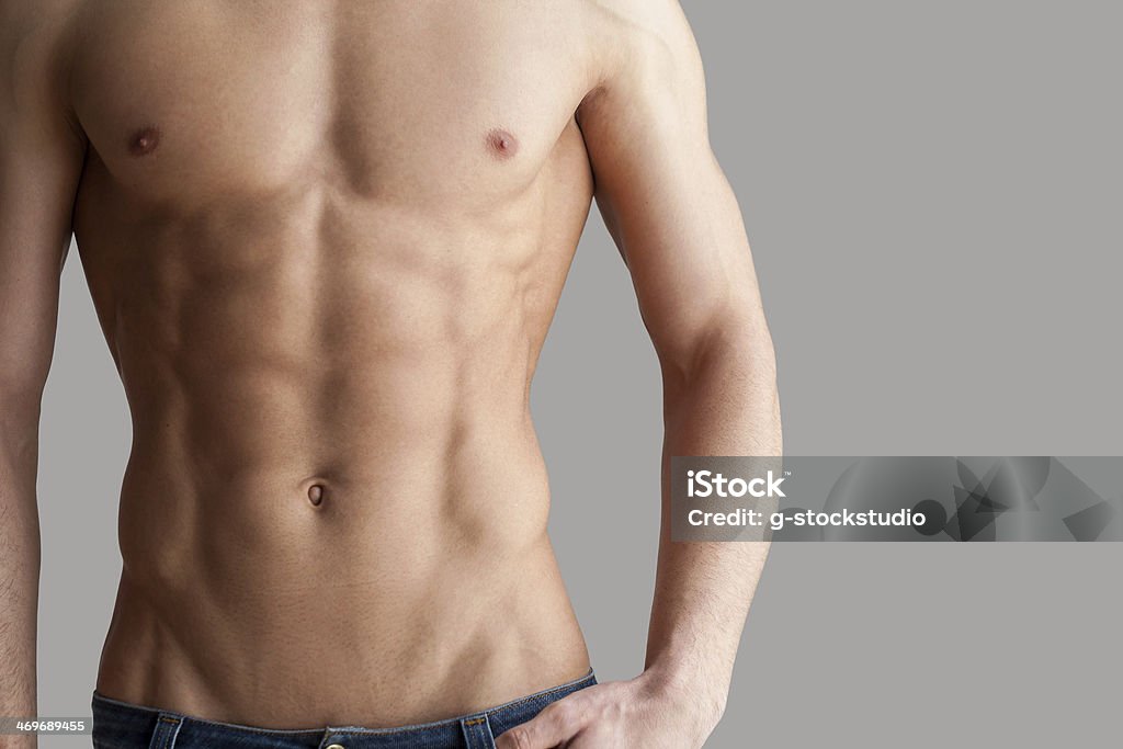 Workout results. Cropped image of muscular man standing isolated on grey background Abdominal Muscle Stock Photo