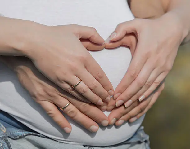 Photo of Four hands on belly of expectant mother