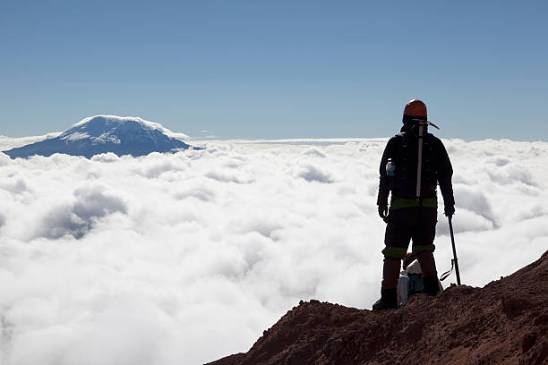 Mountain climber in Cotopaxi Mountain climber in Cotopaxi descending into a sea of clouds and Antisana volcano in the background, Andes Ecuador cotopaxi photos stock pictures, royalty-free photos & images
