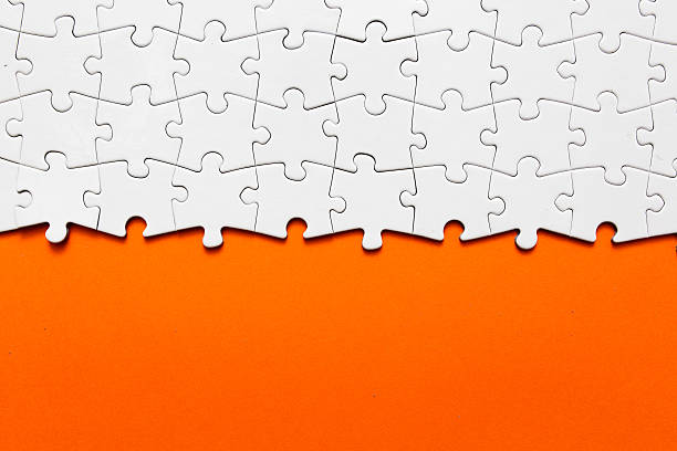 A white jigsaw puzzle with orange background stock photo