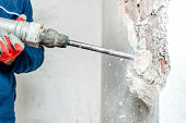 man using a jackhammer to drill into wall
