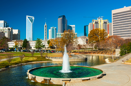 Downtown Charlotte skyscrapers in the background with a park (Marshall Park), fountain and waterway in the foreground.  Picture taken in Autumn.