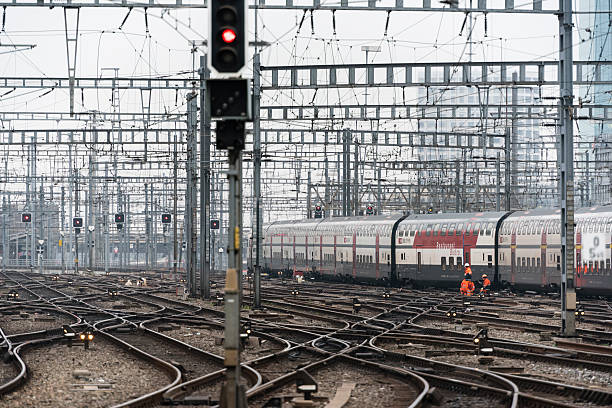 Railway workers on busy Zurich railway station track field Zurich, Switzerland - December 5, 2014: An intercity train of Swiss Federal Railways SBB is leaving Zurich main station with its many railway junctions, overhead contact lines and signals, while railway workers are busy working on the tracks. zurich train station stock pictures, royalty-free photos & images