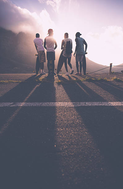 gruppe von teenage skater freunde bei sonnenuntergang - longboard skating stock-fotos und bilder